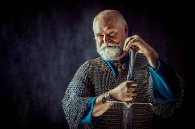 Koyu arka plan üzerinde kılıçla güçlü sakallı knight