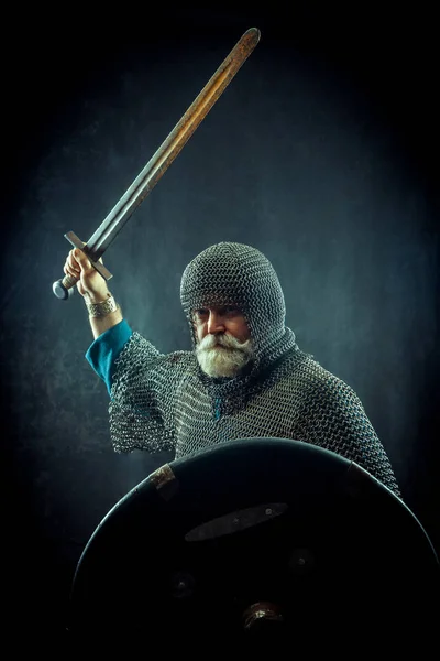 Poderoso cavaleiro barbudo com a espada e escudo no fundo escuro — Fotografia de Stock