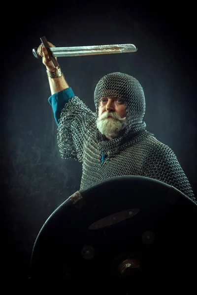 Powerful bearded knight with the sword and shield on the dark background — Stock Photo, Image