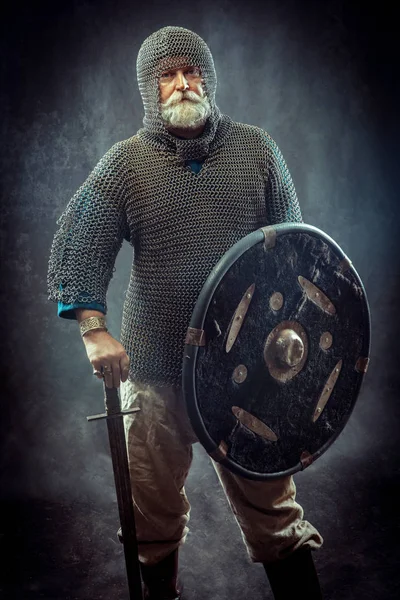 Poderoso cavaleiro barbudo com a espada e escudo no fundo escuro — Fotografia de Stock
