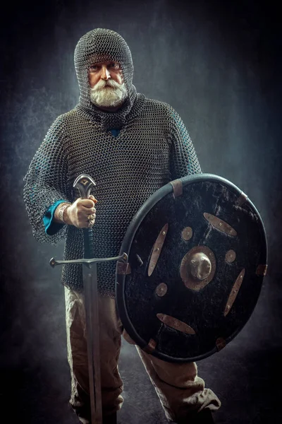 Poderoso cavaleiro barbudo com a espada e escudo no fundo escuro — Fotografia de Stock