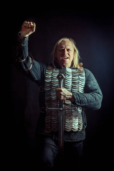 Výkonné blond rytíř s mečem na tmavém pozadí — Stock fotografie
