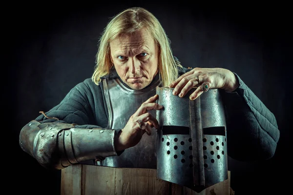 Powerful blond knight with the helmet on the dark background. — Stock Photo, Image