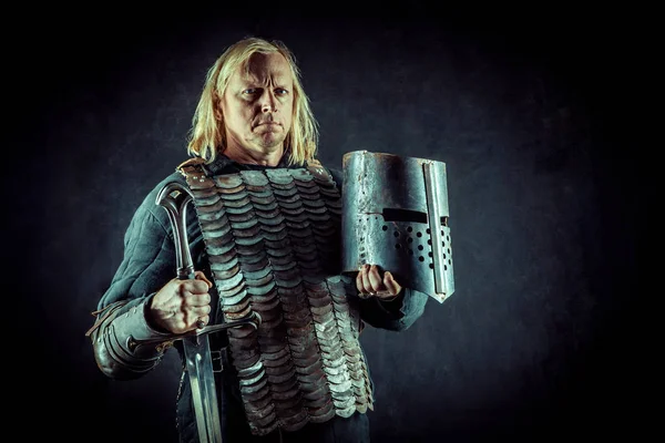 Мощный рыцарь-блондин с мечом и шлемом на темном фоне . — стоковое фото