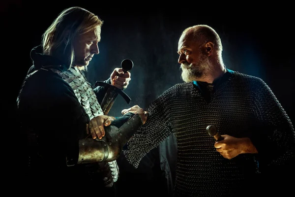 Middeleeuwse ridders steken hun handen in de broederschap van de oorlog. Donkere achtergrond. — Stockfoto
