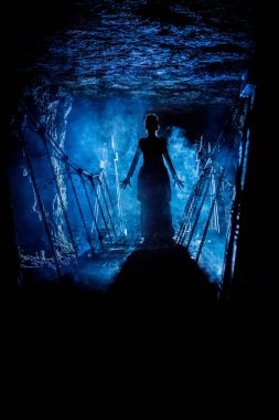 Büyüyü söyleyerek ve elleriyle bize, onu ve zindan köprü etrafında duman bulutları arka plan üzerinde uzanan gizemli bir cadı silüeti