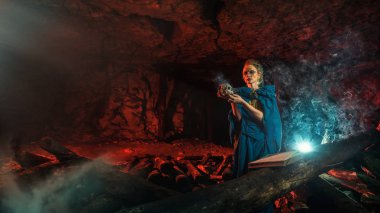 Kafatası ile güzel kırmızı saçlı cadı. Koyu arka plan.