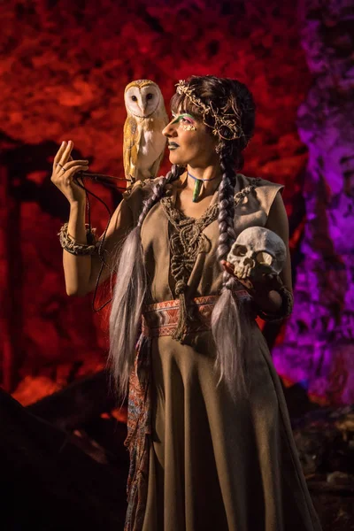 Krásná čarodějka s bílá sova a lebky v ruce. — Stock fotografie