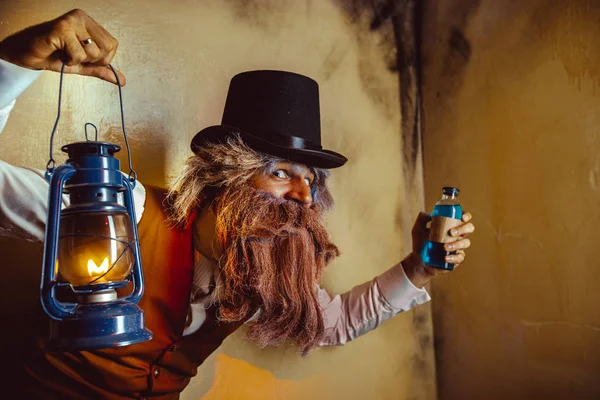 Bearded man wearing black hat and vest with the lantern. Medicine man in Dickens style. — Stock Photo, Image