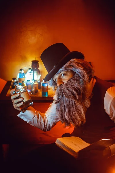 Bebaarde man met het boek in de ene hand en de fles in een andere — Stockfoto