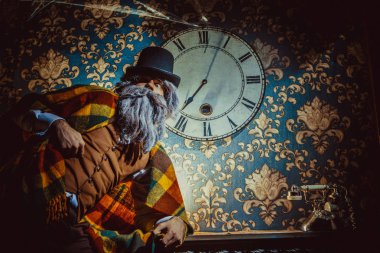 Üst düzey Beyaz adam karanlık odada duvara saatin yanında ayakta.