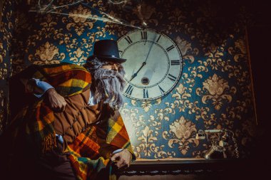 Üst düzey Beyaz adam karanlık odada duvara saatin yanında ayakta.