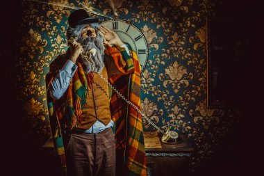 Karanlık odada duvara saatin yanında duran ve telefonda konuşurken üst düzey Beyaz adam.