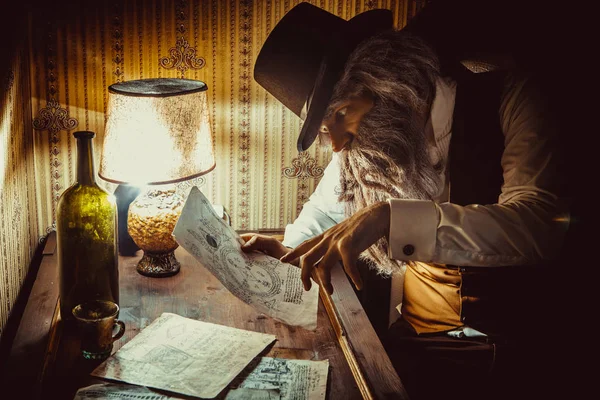 Bebaarde man leest een geheimzinnige brief in de donkere kamer — Stockfoto