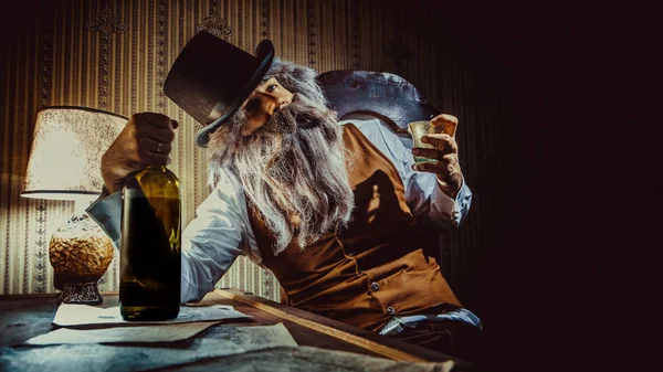 Vousatý muž pije whisky v temné místnosti. — Stock fotografie
