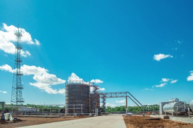 Petrol sahası geliştirme, arka planda büyük petrol tankları.