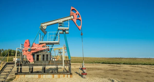 Pumpeneinheit arbeitet im Ölfeld auf der grünen Wiese — Stockfoto