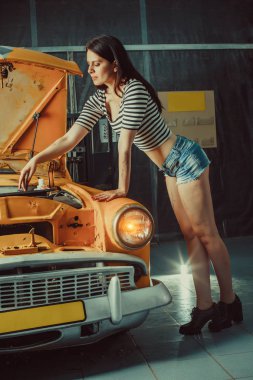 Eski model araba yakınındaki seksi şortlu kadın makinist