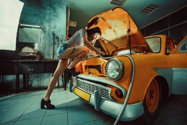 Sexy woman is welding something inside an old car. — Stock Photo, Image