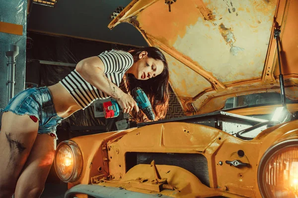 Jovem mulher sexy mecânico está fixando o motor na garagem de reparação — Fotografia de Stock
