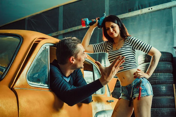 Woman mechanic in sexy shorts is listening to the customer — Stock Fotó