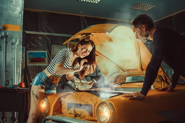 セクシーなショート パンツの女性メカニックは古い車を修理します。. — ストック写真