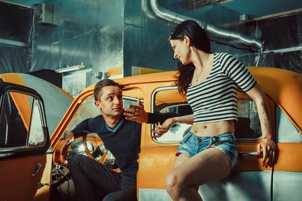 Woman mechanic in sexy shorts is listening to the customer — Stock Fotó