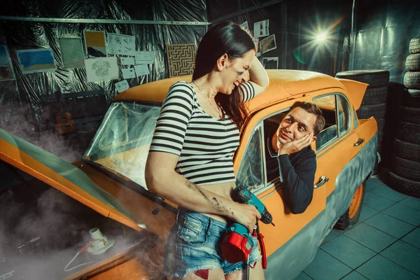 Woman mechanic in sexy shorts is listening to the customer — Stock Photo, Image