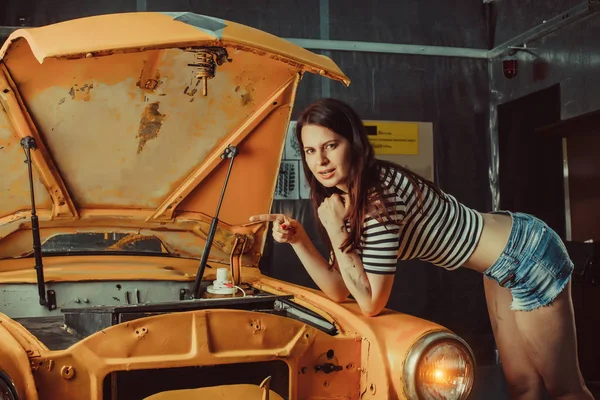 Eski model araba yakınındaki seksi şortlu kadın makinist