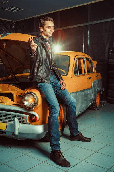 Motorista inteligente está sentado em seu carro velho na garagem — Fotografia de Stock