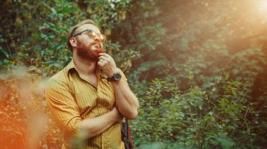 Sakallı bir backpacker orman arka plan üzerinde sırt çantası ile portresi