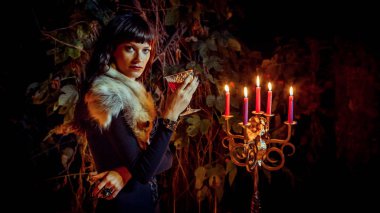 Asma gece orman arka plan üzerinde bardak ile güzel cadı.