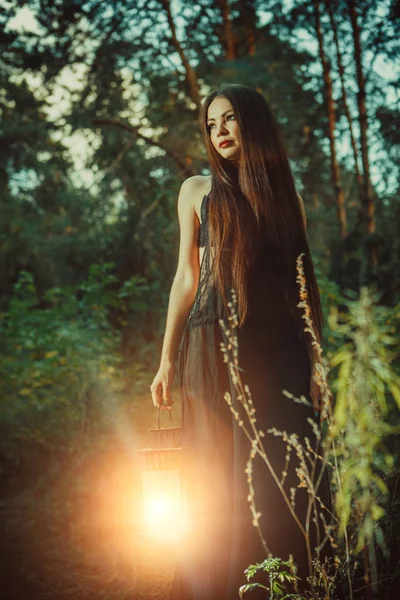 Krásná čarodějka s magic lantern vás zve do lesa. — Stock fotografie