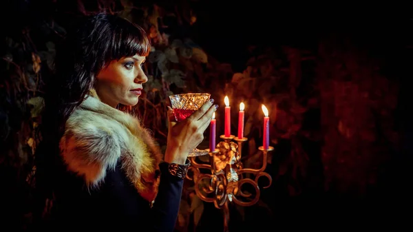 Όμορφη μάγισσα με το ποτήρι του αμπελιού στο φόντο δάσος νύχτα. — Φωτογραφία Αρχείου