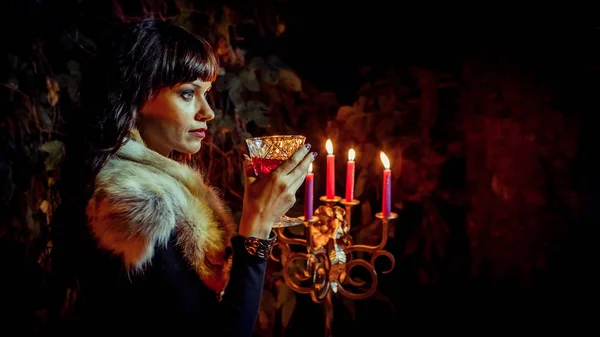 Hermosa bruja con el vaso de vid en el fondo del bosque nocturno . — Foto de Stock