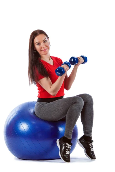 Fitnessfrau trainiert mit den Hanteln und dem Fitnessball. — Stockfoto