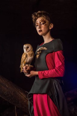 Güzel genç cadı ile beyaz baykuş. Koyu arka plan.