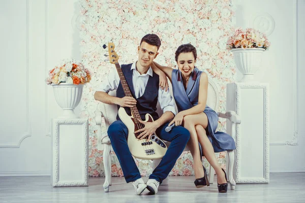 Pareja joven está sentada en el sofá con la guitarra eléctrica . — Foto de Stock