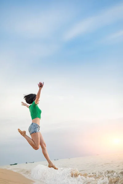 Mujer caucásica relajándose en la orilla del mar. Puesta de sol en el fondo . — Foto de Stock