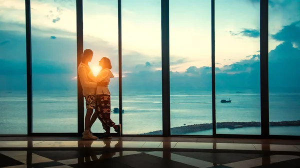 美丽的夫妇从全景窗口欣赏大海的落日 — 图库照片