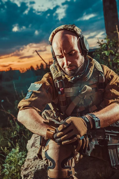 Americký voják s puškou M4 má odpočinek. Západ slunce na pozadí. — Stock fotografie
