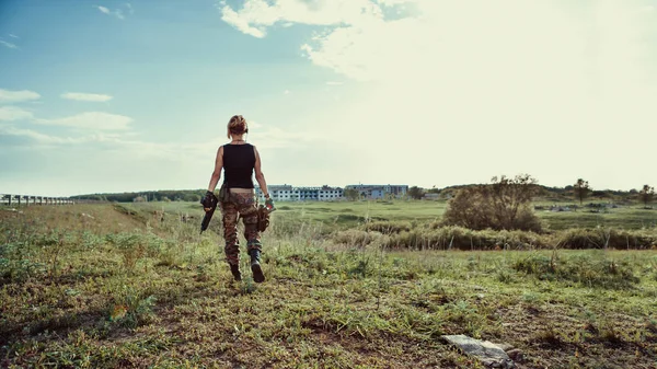 Soldado mulher com a espingarda no fundo da cidade arruinada . — Fotografia de Stock