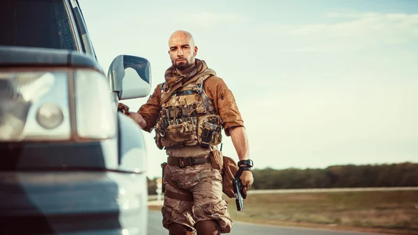 Soldier in american uniform with the pistol . Military SUV on th — Stock Photo, Image