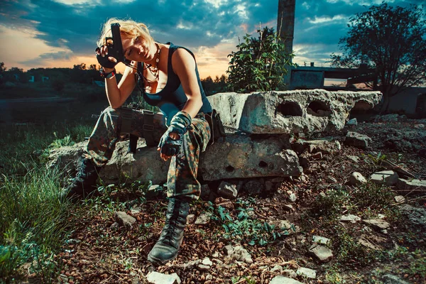 Sexy vrouwelijke soldaat met pistool rust. Zonsondergang op de b — Stockfoto