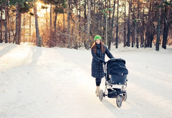 Mulher com buggy bebê no parque de inverno — Fotografia de Stock