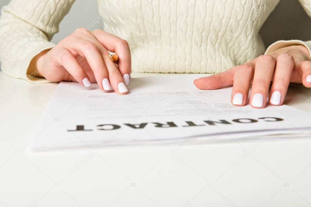 Female hands examining contract on white table