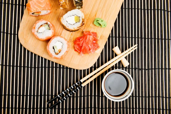 用酱油和棍子在木板上贴上寿司的特写 — 图库照片