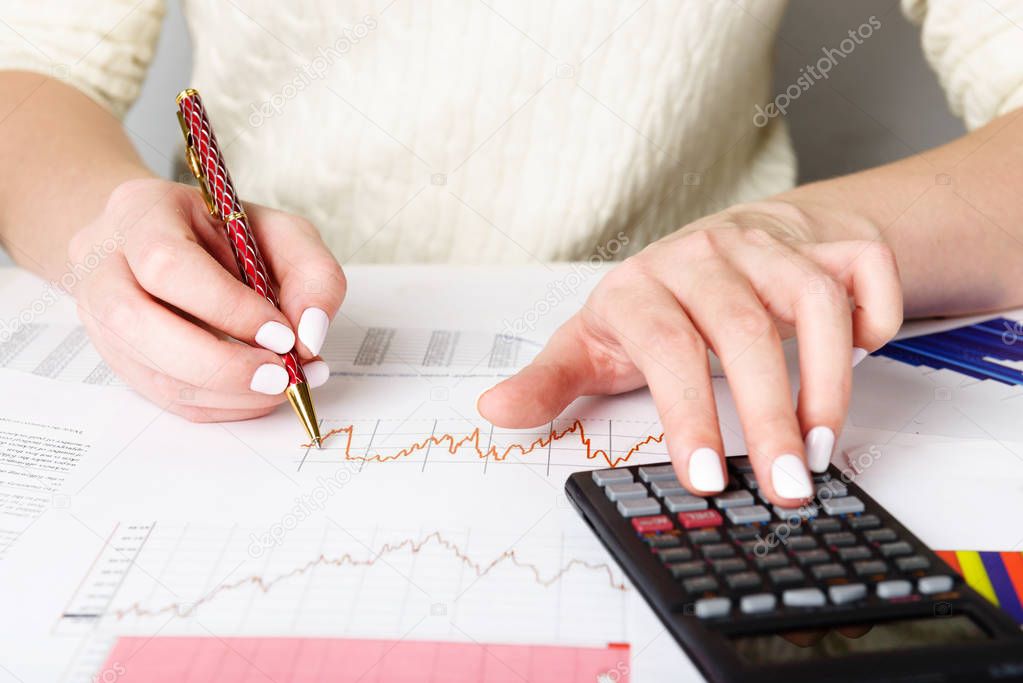 Business analyst working - hand with pen, calculator, sheet and graph