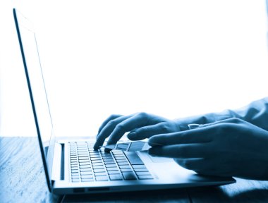 Eller kredi kartını tutuyor ve online alışveriş için dizüstü bilgisayar kullanıyor.