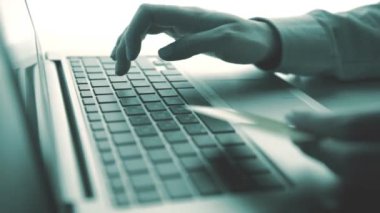 Bir kredi kartı tutan ve online shoppin için dizüstü bilgisayar kullanan eller